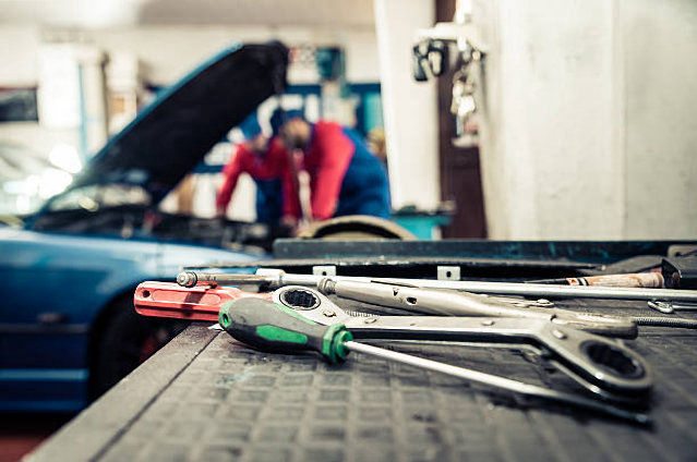 tools on bench with mechanics working on car in background